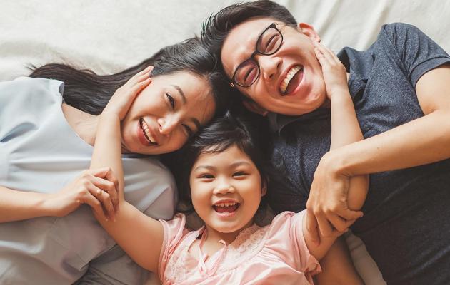 A happy family laying on a bed. 