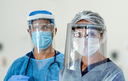 Two healthcare workers with face shields and face masks.