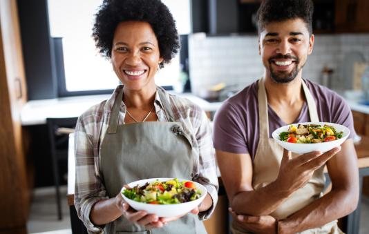 Two happy chefs presenting the meals that they prepared