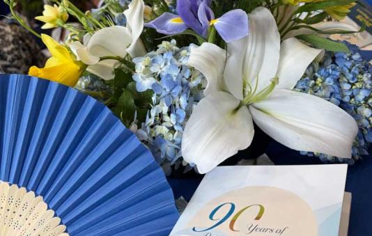 Flower decor and a booklet whose cover reads "90 Years of Putting Members First"