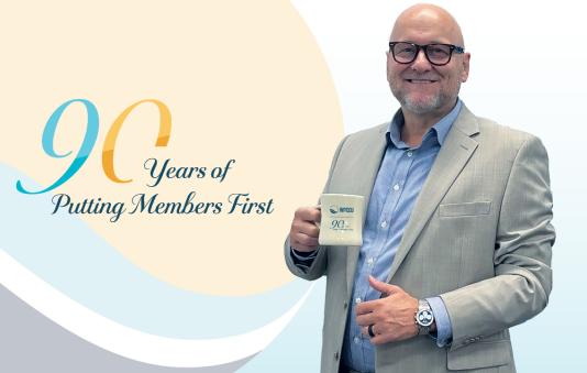 Mike Tufegdzich, President/CEO, holding a coffee mug. 