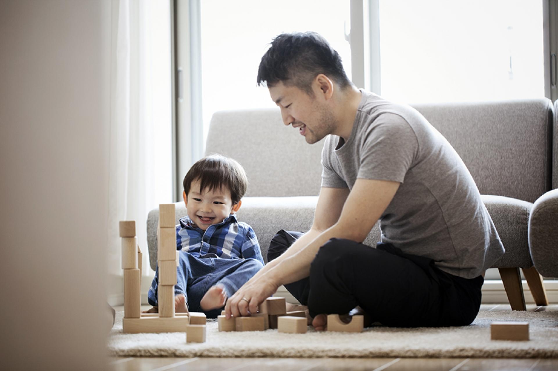 A man sitting with a child playing with blocks.