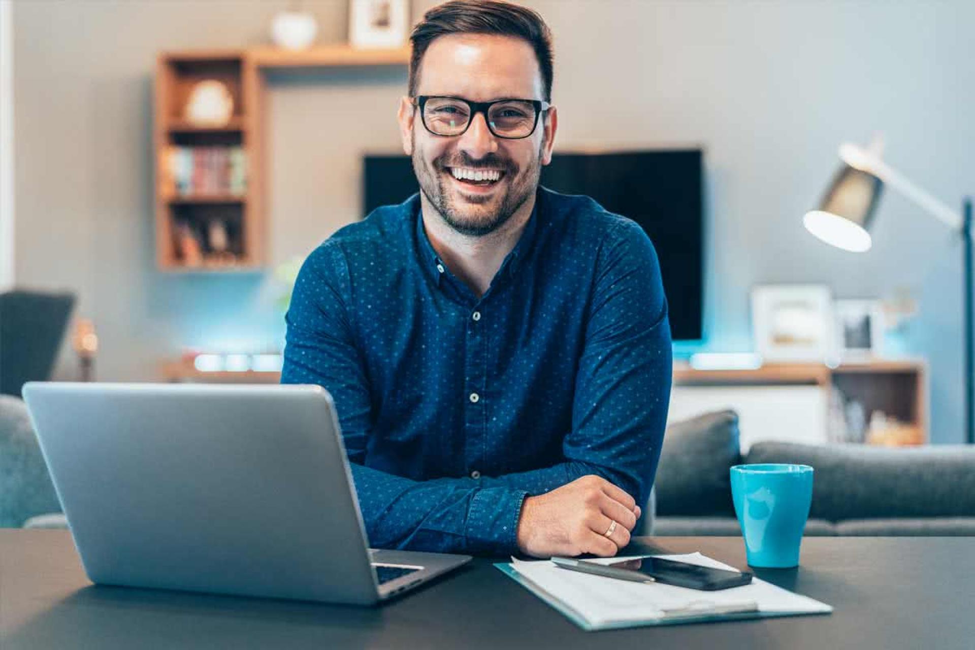 Man with glasses and a laptop smiling
