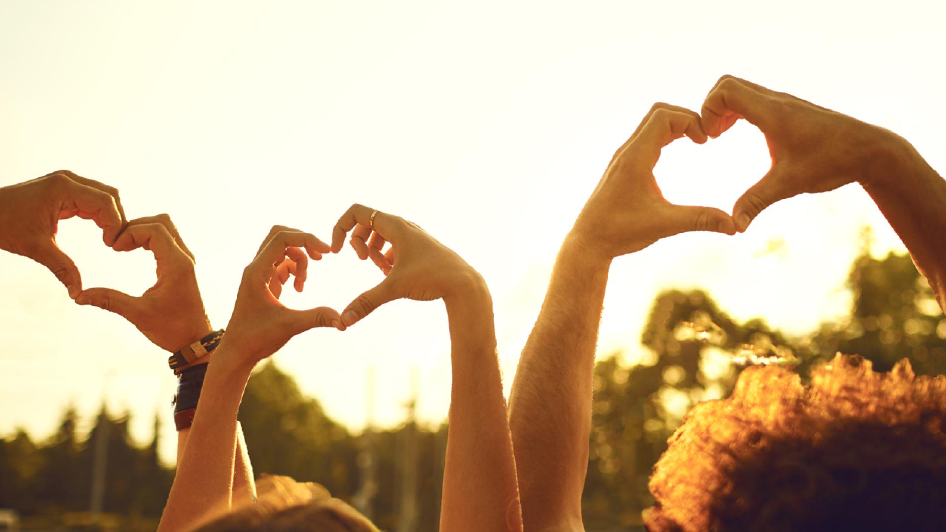 Group of friends forming heart shapes with their hands. 
