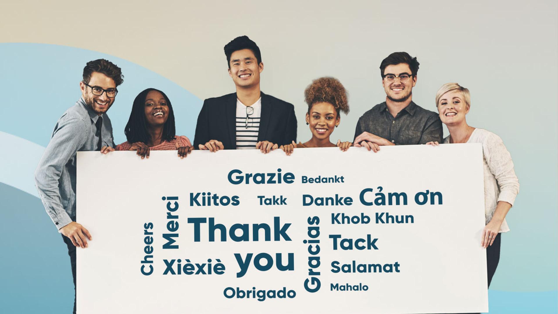 Persons holding a sign displaying "Thank you" in various languages.