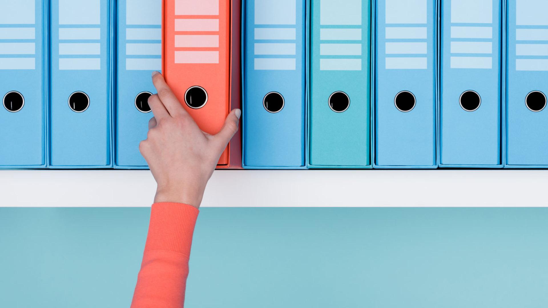 Person taking a folder off a shelf.