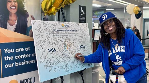 Member signing a 90th Anniversary poster