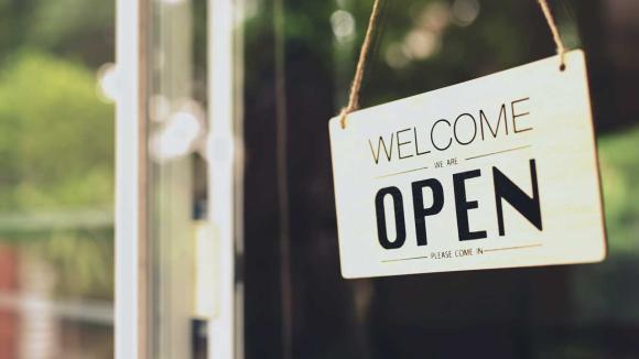 A sign displaying "Welcome: We're open"