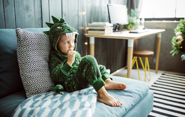 Child wearing a dinosaur costume watching TV