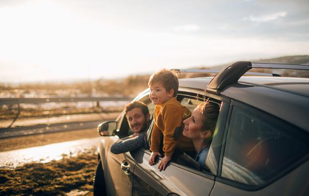 A family enjoying the sun in their car on the beach.