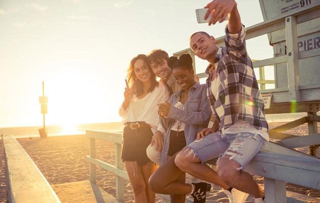 A group of people on the beach taking a selfie.