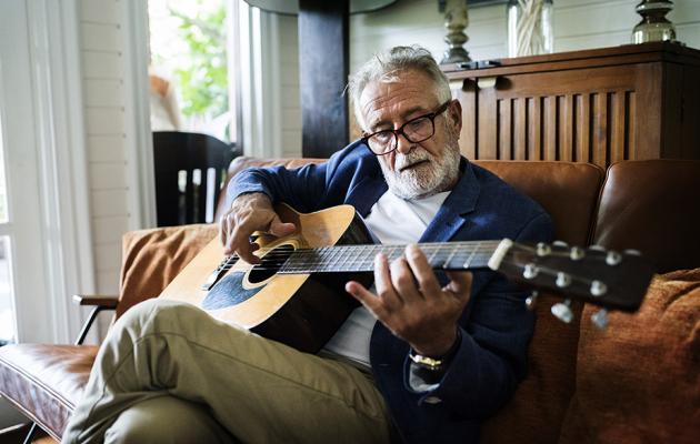 Senior man playing guitar in living room