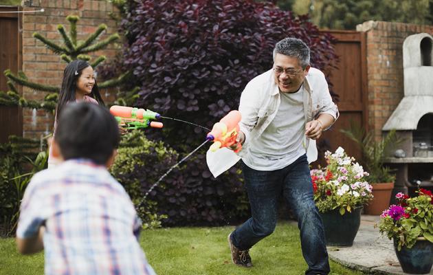 Family playing with water guns on front lawn