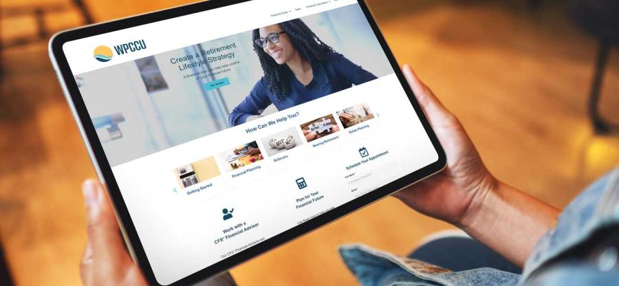 A woman is holding a tablet. The display of the tablet displays a new website.
