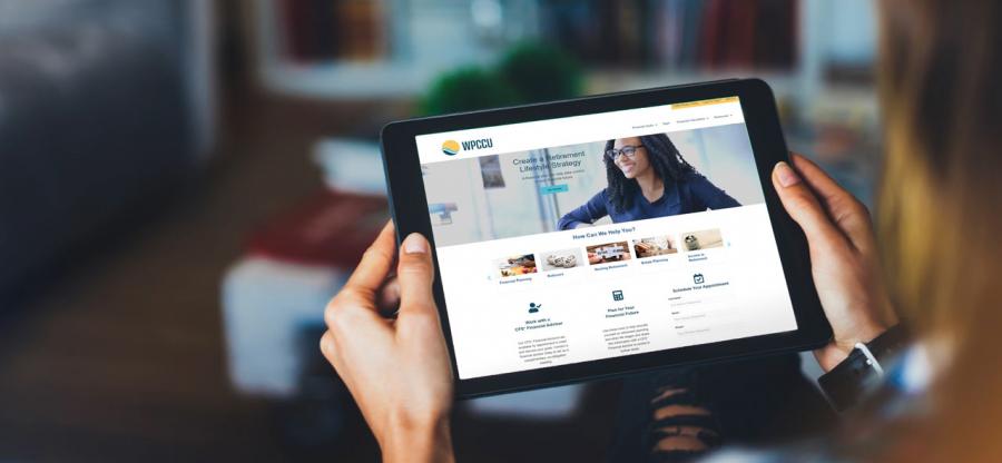 A woman is holding a tablet. The display of the tablet displays a new website.