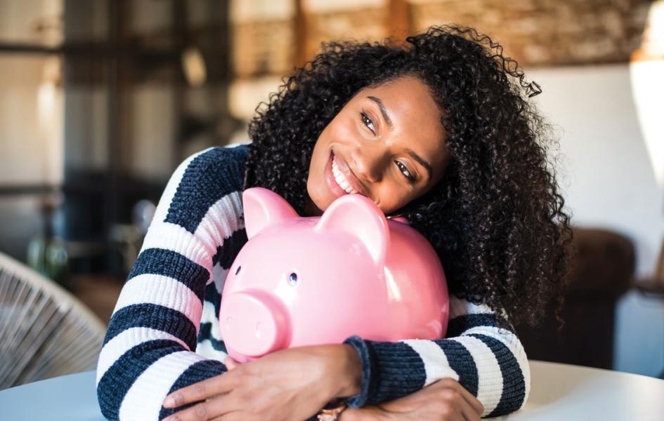 A woman hugging an oversized piggy bank.