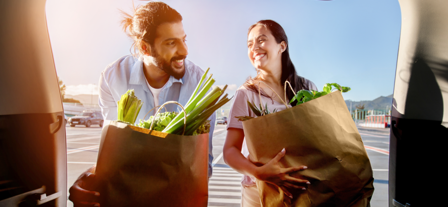 Two people packing the trunk of a car with groceries. 