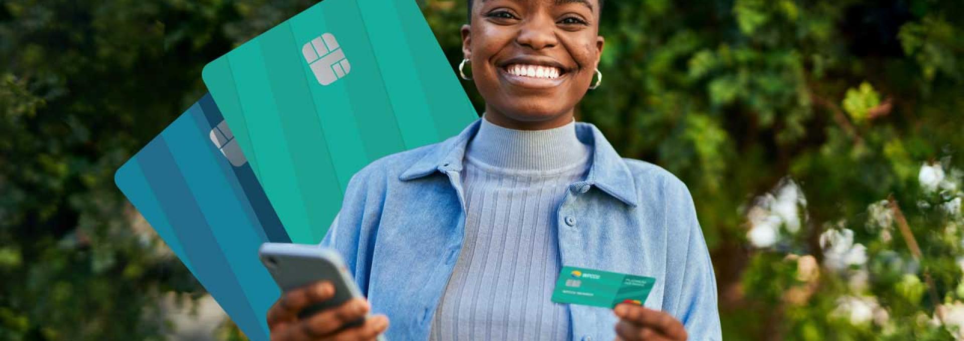 A photo of a woman. She is holding a credit card in her left hand and a smartphone in her right.