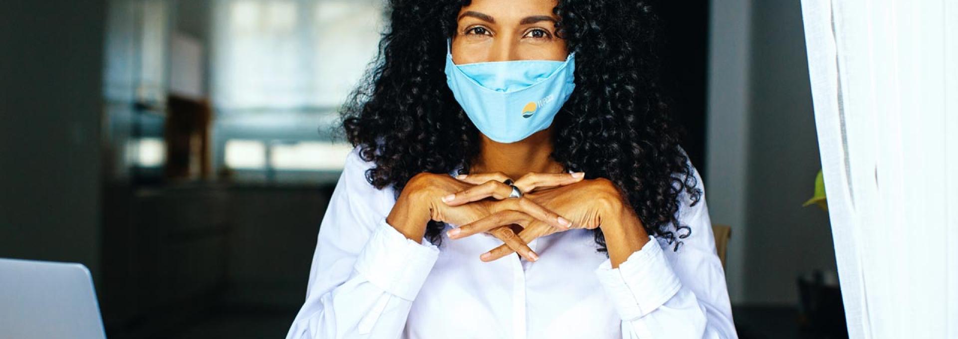 A woman with a face mask looking at the camera. 