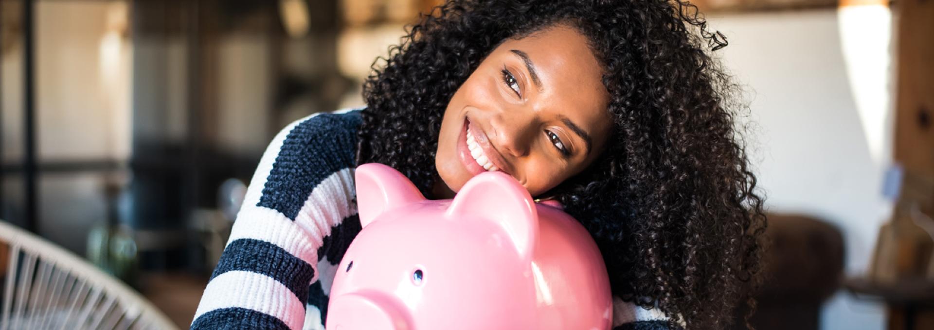 A woman hugging a large piggy bank.