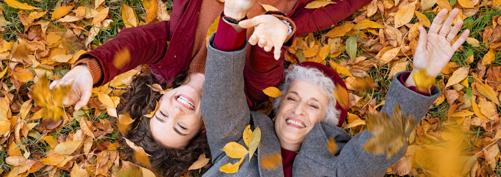 Two persons lying on foliage, enjoying the fall season.