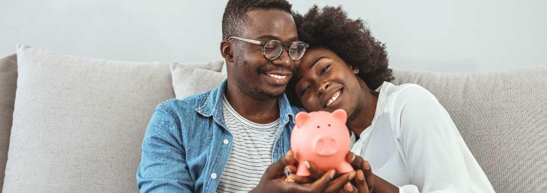 Two persons holding a piggy bank. 