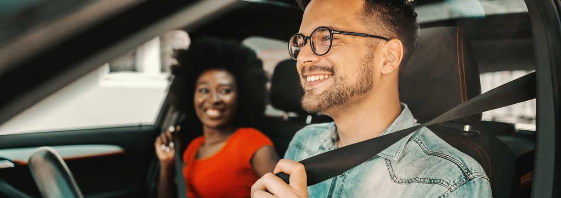 Two people fastening their seatbelts in a car.